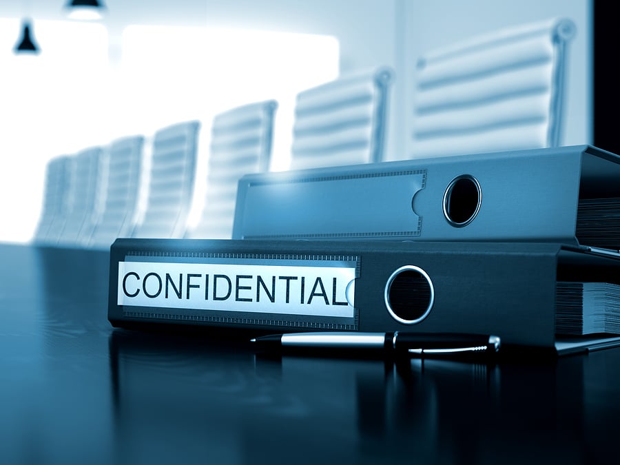 Confidential binders stacked on a conference room table