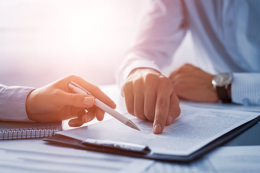 Two people reviewing and pointing at a document together