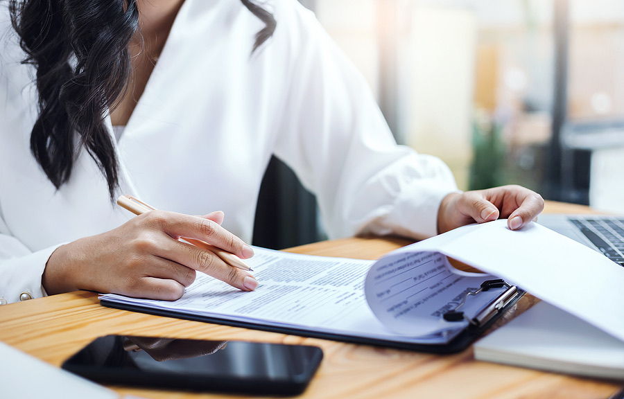 Businesswoman reviewing a document on a clipboard at her desk