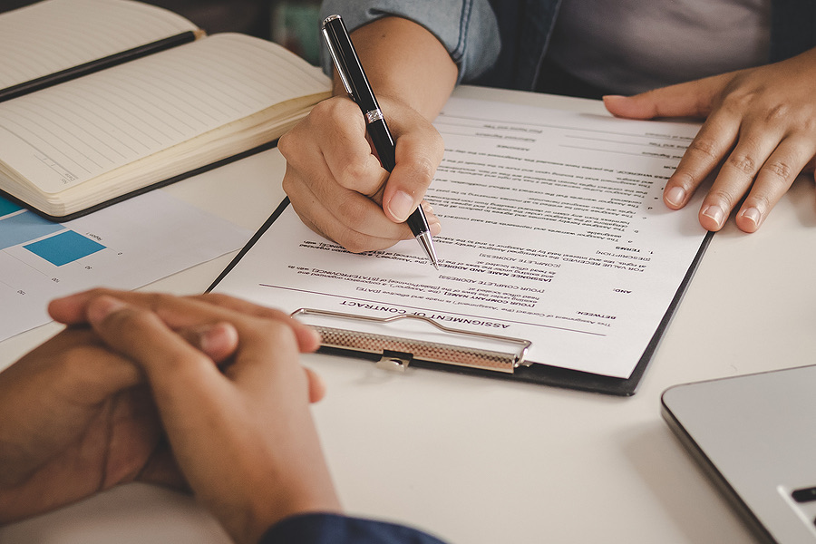 Person signing a lease document while another looks on