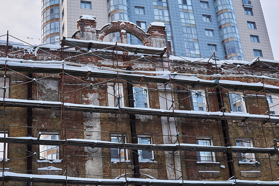 Scaffolding around a crumbling brick building facade