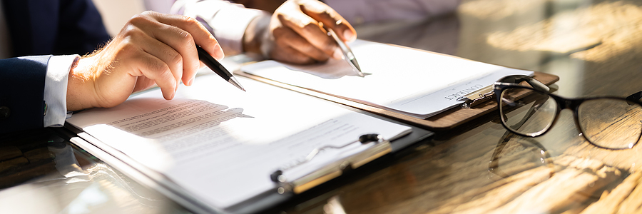 Close-up of hands reviewing and signing a contract document