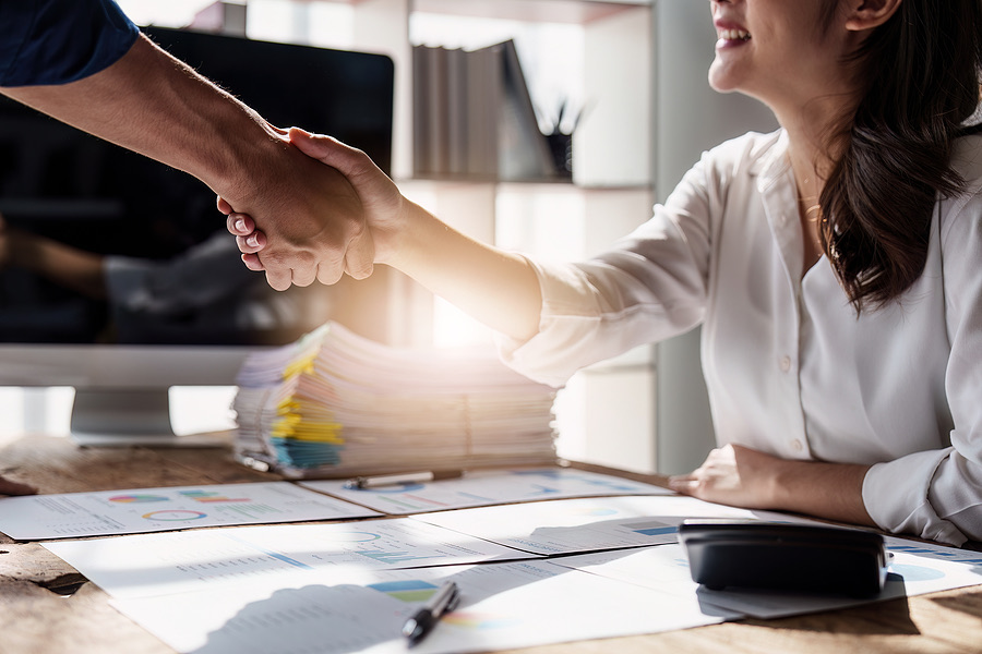 Smiling woman shaking hands with a colleague over paperwork