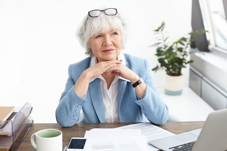 Businesswoman sitting confidently at her desk with hands clasped