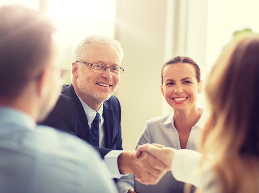 Smiling business owner shaking hands with a colleague across a table
