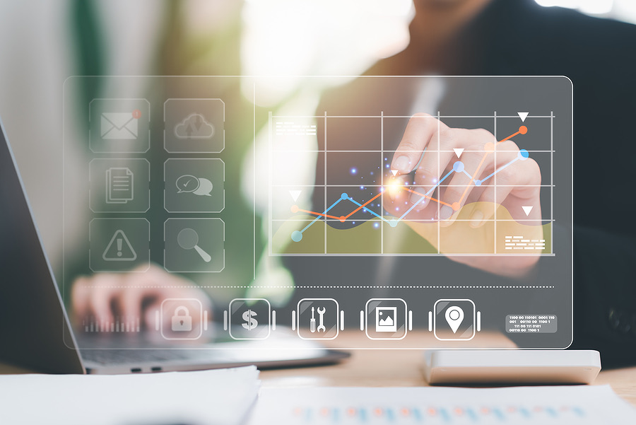 Hand pointing to a rising line chart on a digital business dashboard