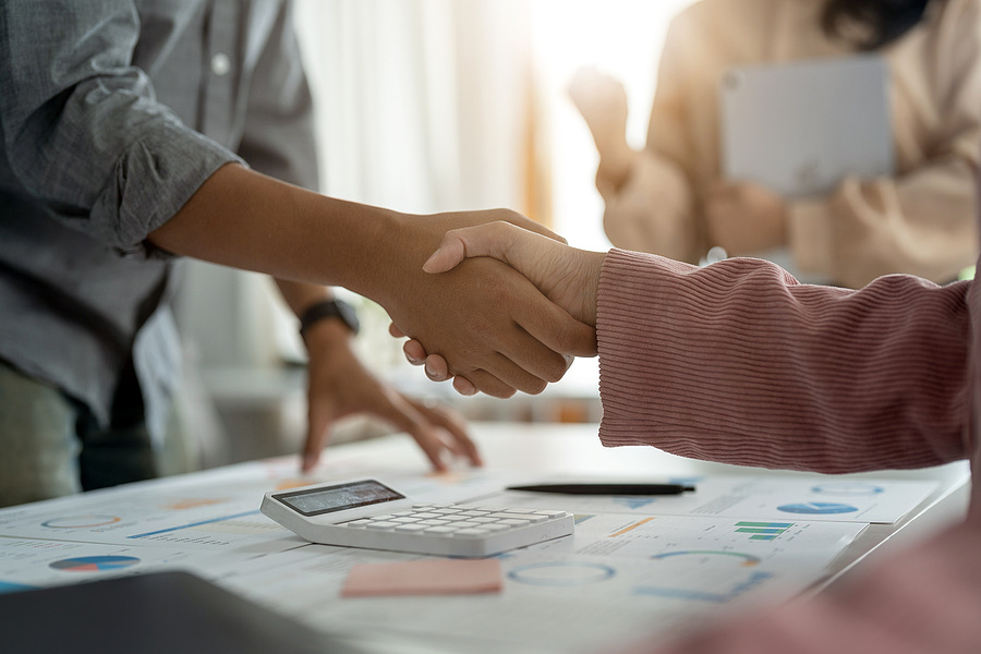 Close-up handshake between two professionals at a desk
