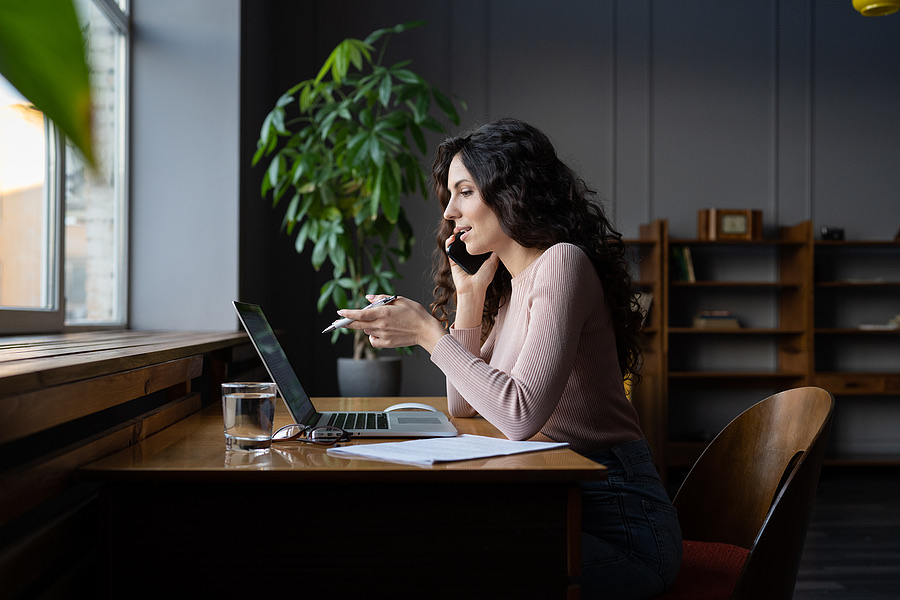 Businesswoman on a phone call while working at her laptop