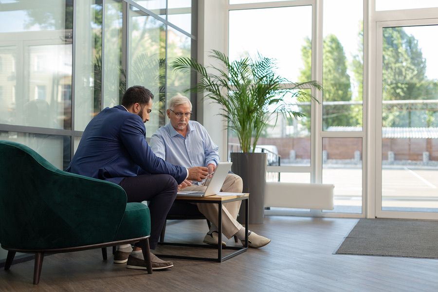 Two colleagues reviewing a laptop together in a lounge area