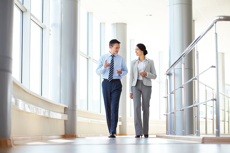 Two business professionals walking and talking in an office hallway