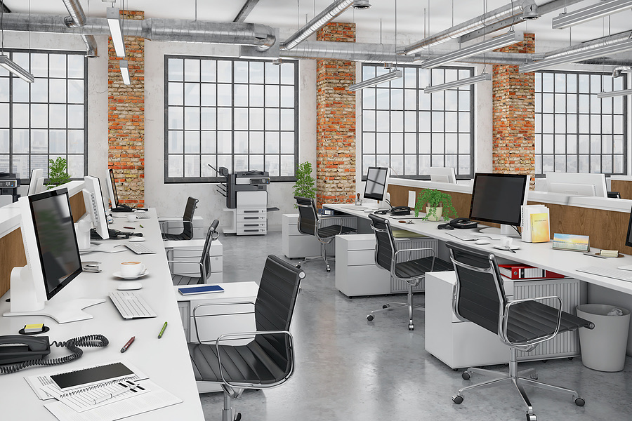Empty open-plan office with rows of desks and computers