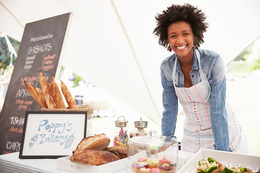 Smiling bakery owner standing behind her market stall