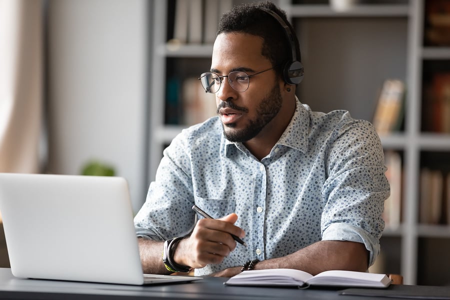 Man wearing headphones working at a laptop in a home office