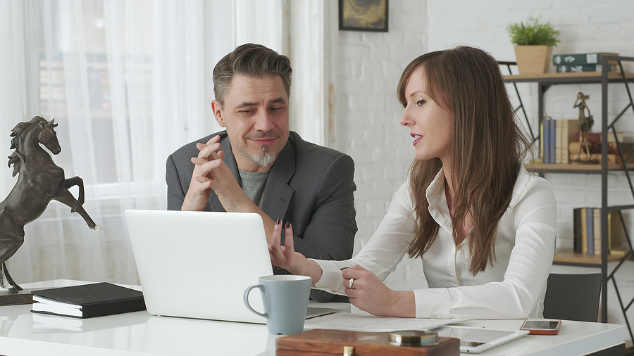 Two colleagues discussing work at a laptop in an office