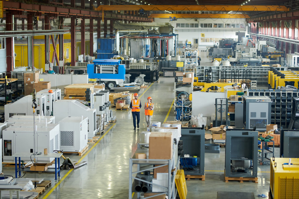 Warehouse workers walking through a factory floor with machinery