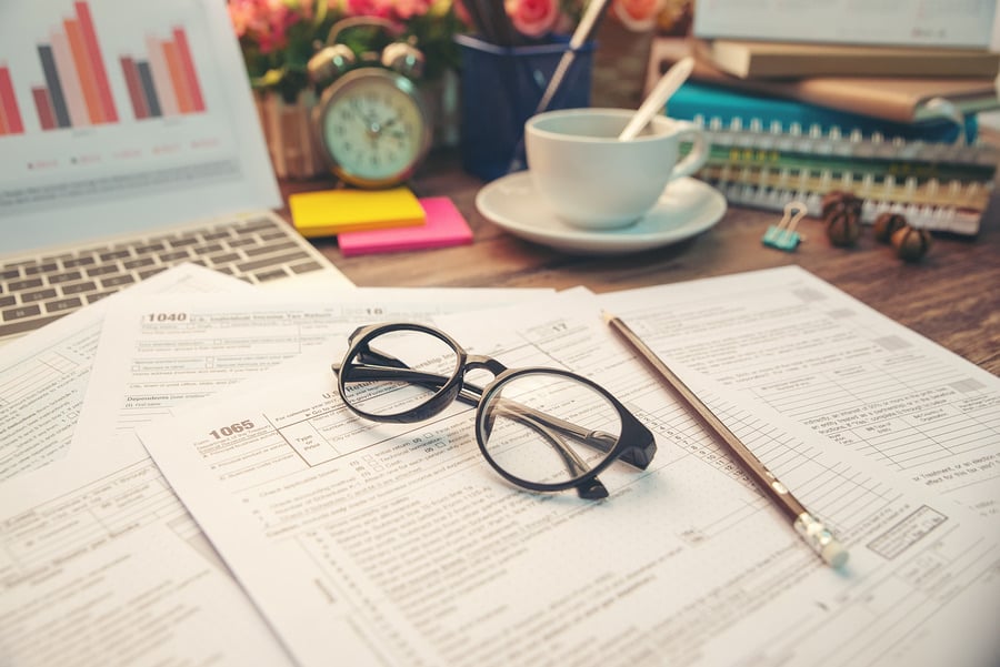 Tax forms with glasses, a pen and a cup of coffee on a desk