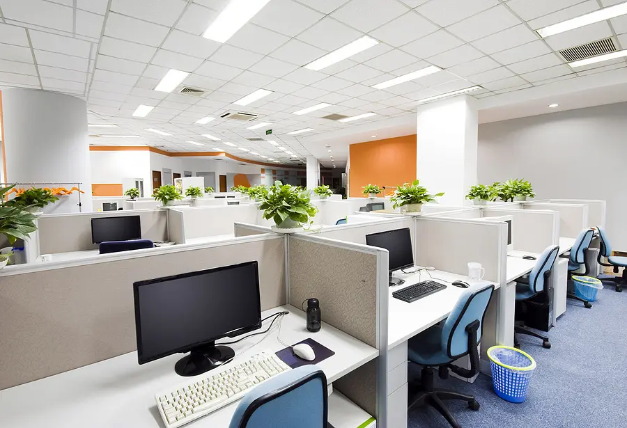 Rows of empty desks and computers in an open-plan office