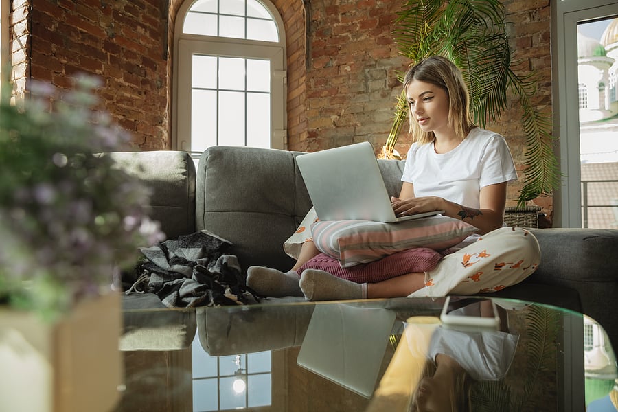 Person working remotely on a laptop from a home sofa