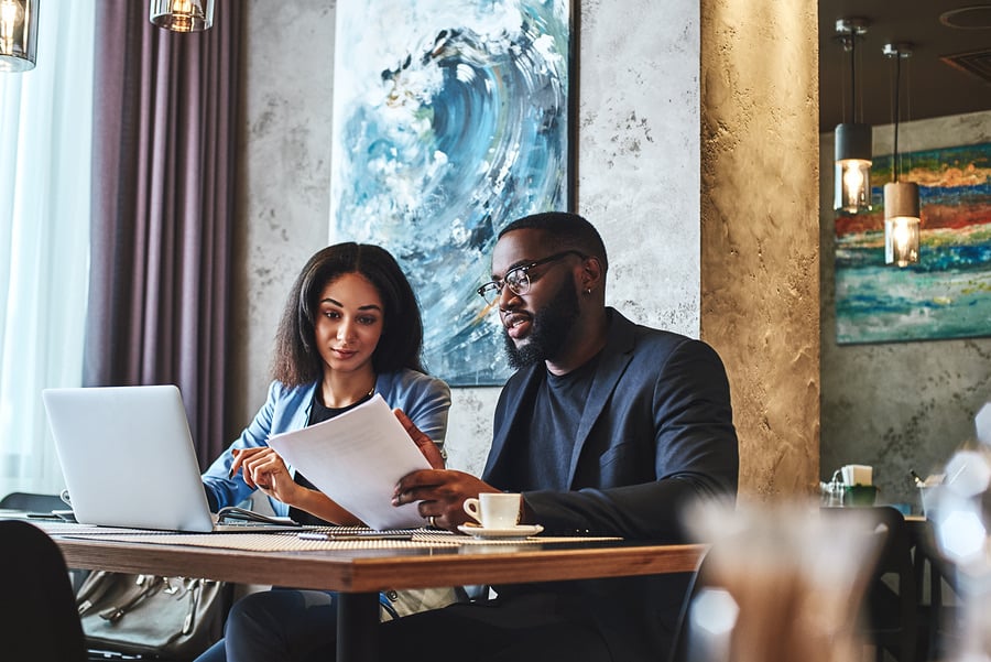 Two colleagues reviewing documents together at a cafe table