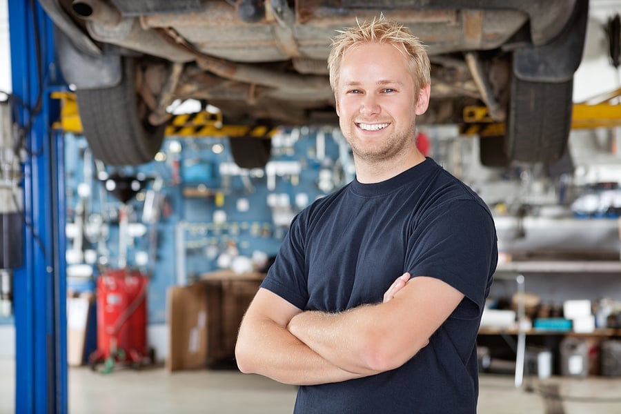 Smiling mechanic standing with arms crossed in an auto shop