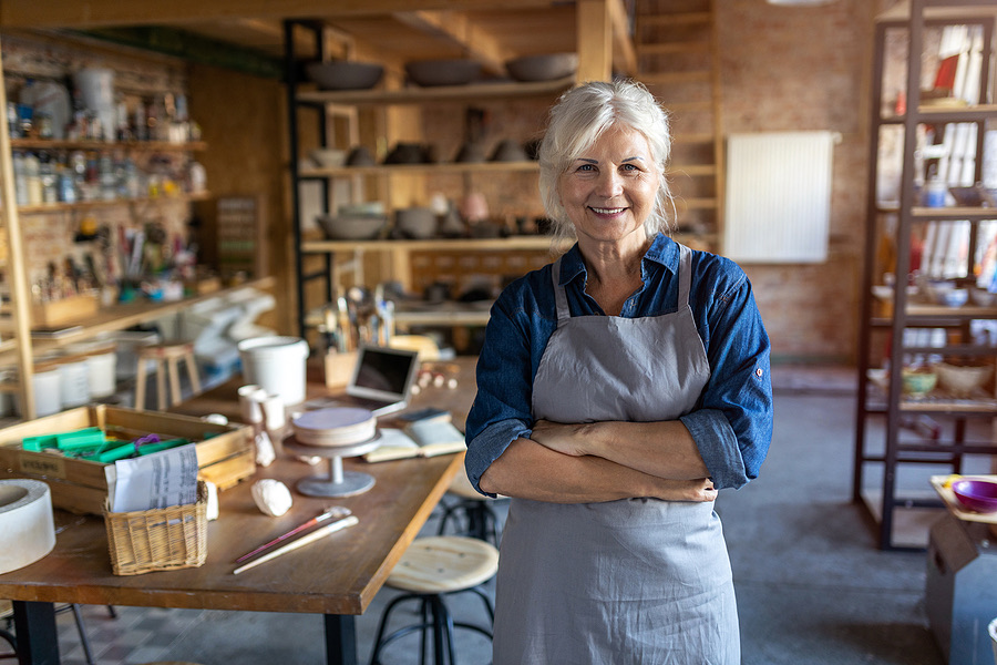 Smiling pottery studio owner standing with arms crossed