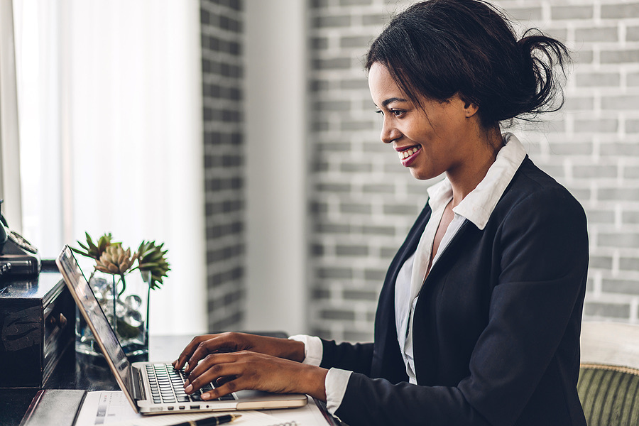 Smiling employee typing on a laptop at her desk