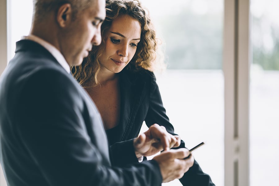 Two professionals looking together at a smartphone screen
