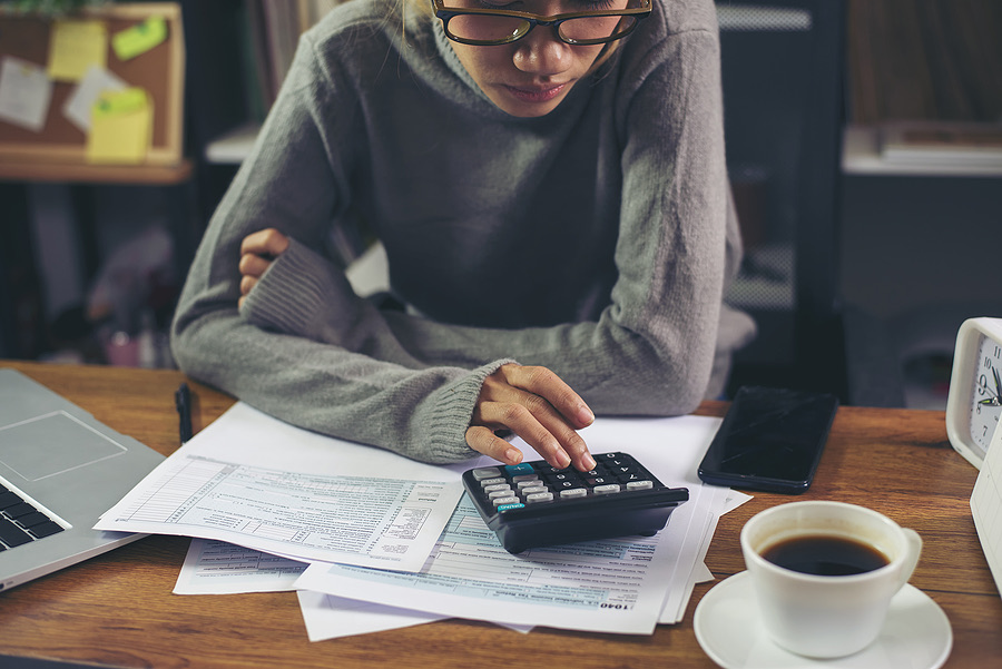 Person using a calculator while reviewing tax paperwork