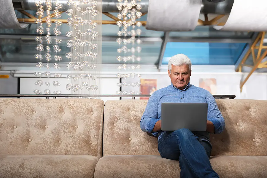 Senior business owner working on a laptop on a couch