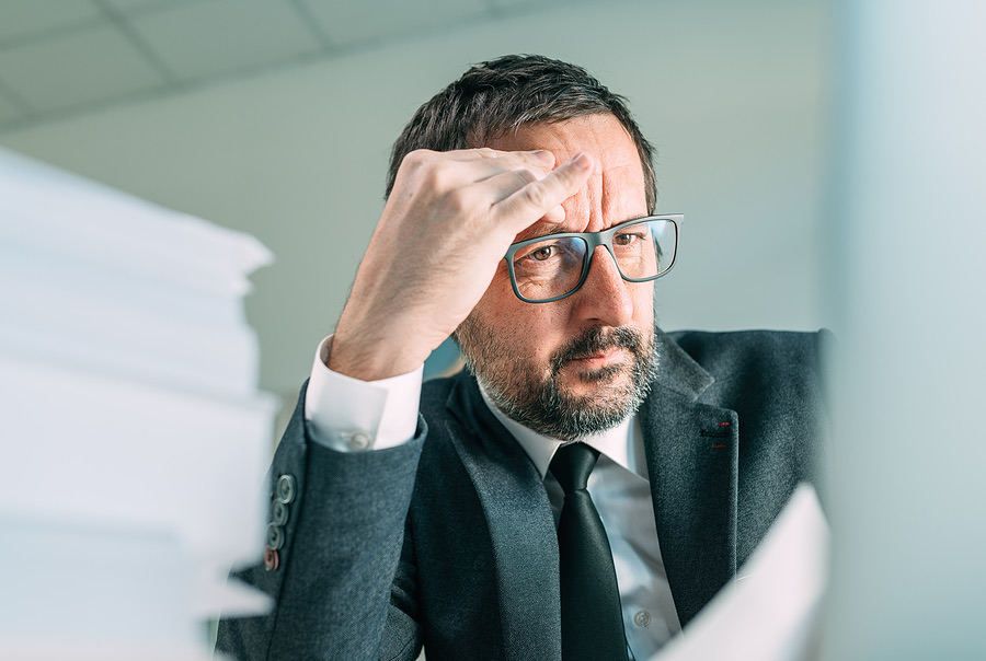 Stressed executive rubbing his forehead over paperwork
