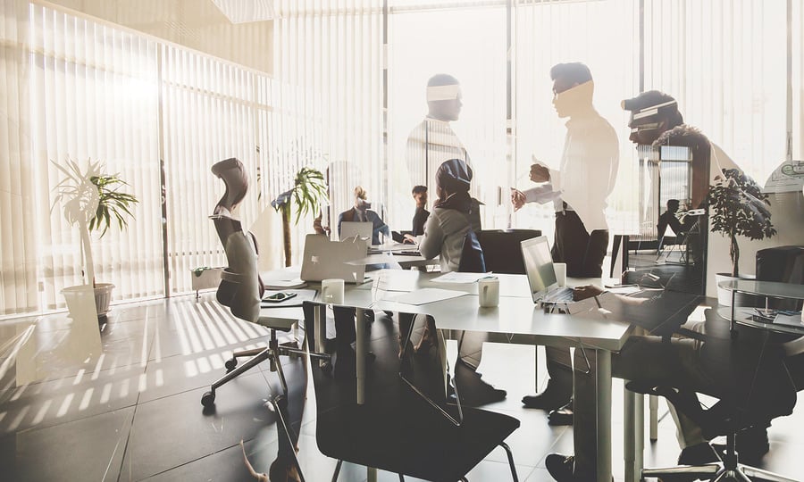 Silhouettes of colleagues working at desks in a bright office