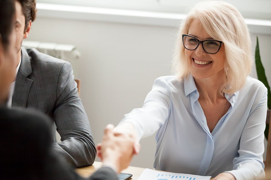Two colleagues shaking hands across a meeting table