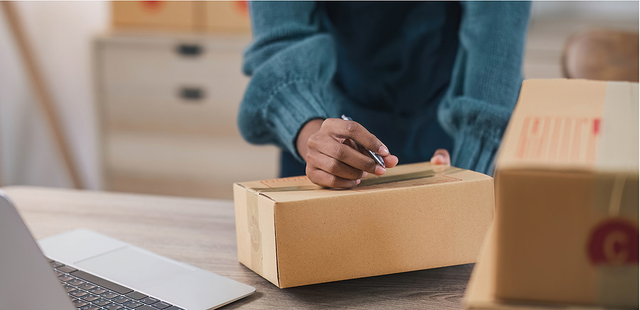 Person taping up a shipping box on a home desk