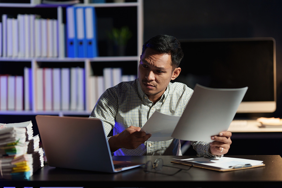 Man reviewing paperwork at a desk late at night
