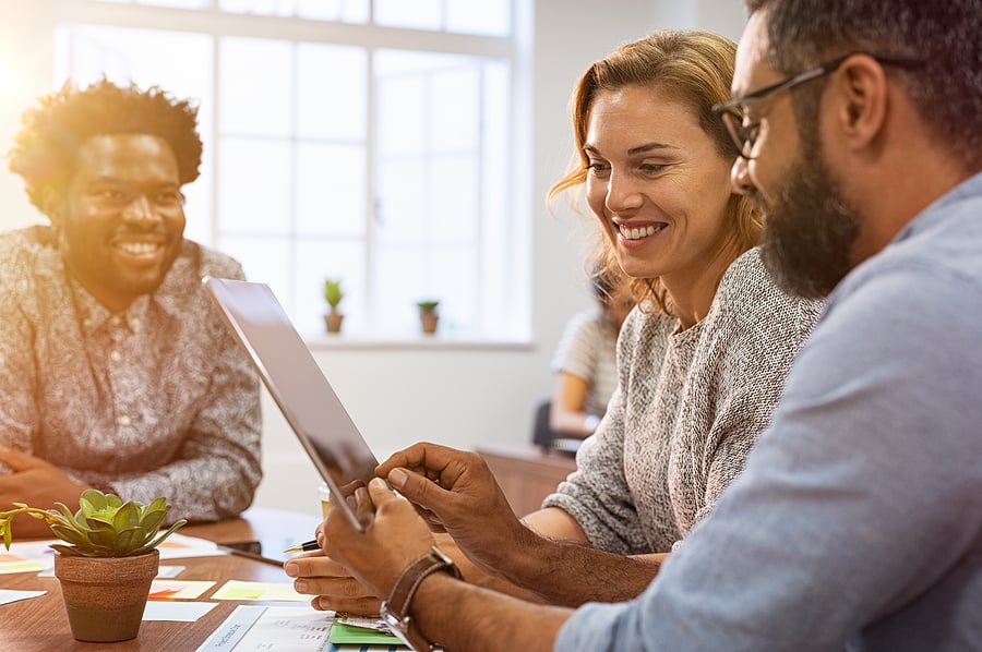 Colleagues smiling together while looking at a laptop