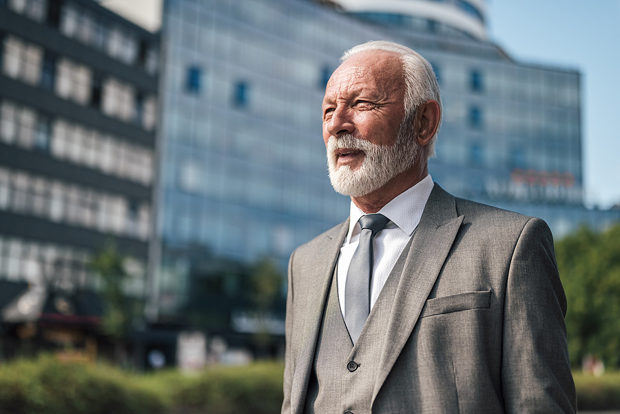 Senior businessman standing outside a modern office building