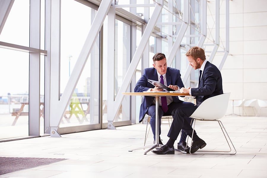 Two businessmen discussing documents at a small table