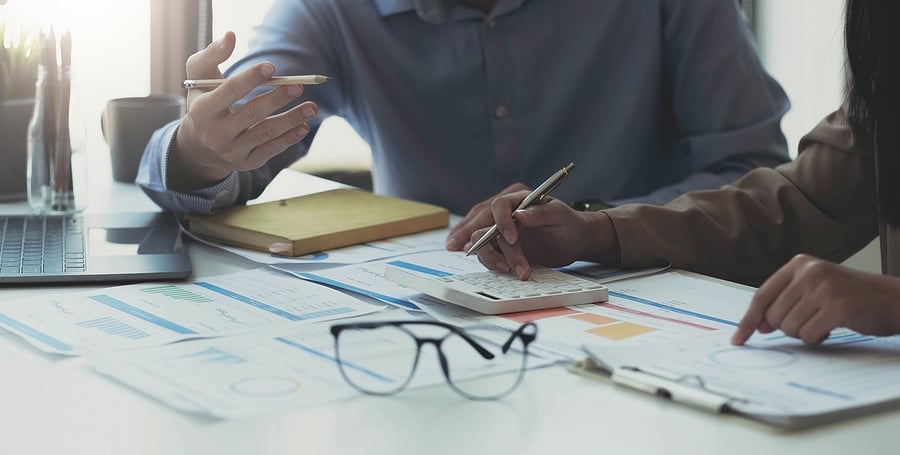 Colleagues reviewing financial charts and a calculator on a desk