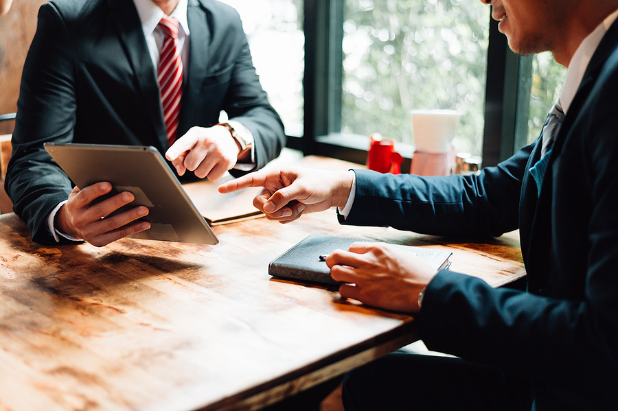 Two businessmen discussing a tablet across a table