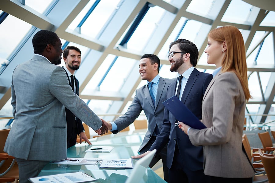 Group of professionals shaking hands in a glass office lobby