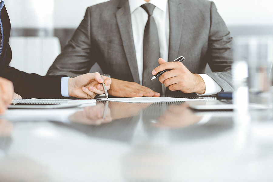 Two professionals signing documents at a conference table