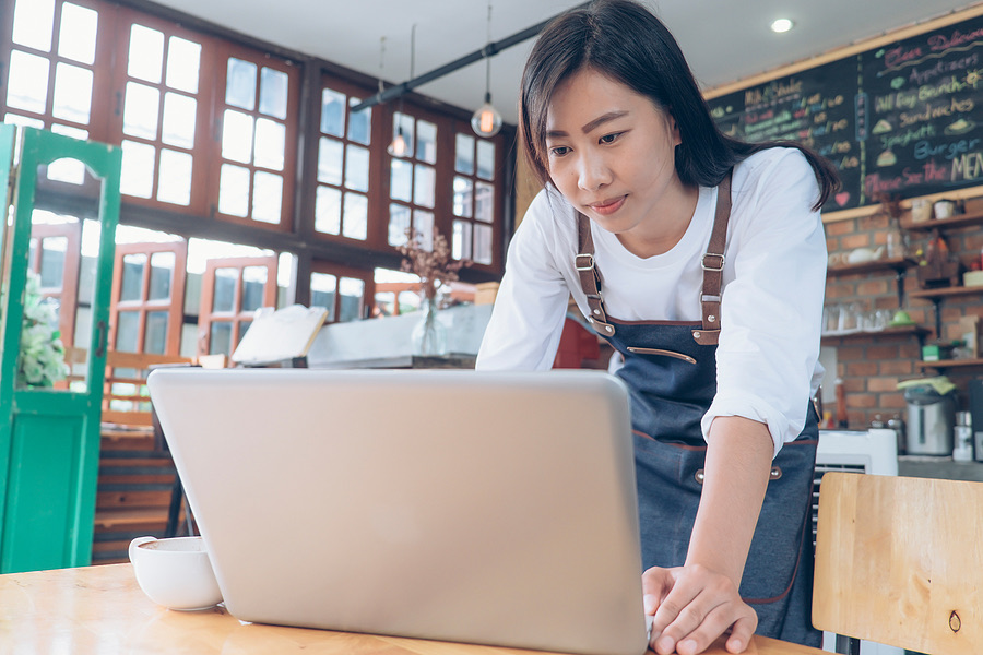 Cafe owner using a laptop at the counter