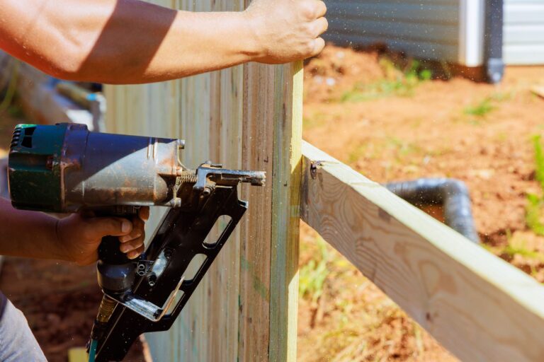 Contractor using a nail gun to build a wooden fence